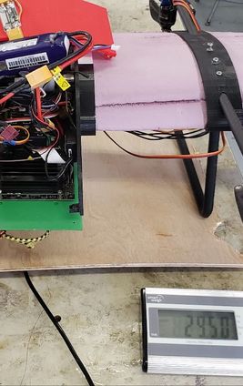 Avionics and battery mounted to the fuselage, sitting on a digital scale
