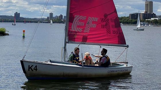 Small sailboats racing on the Charles River basin in front of the Boston skyline